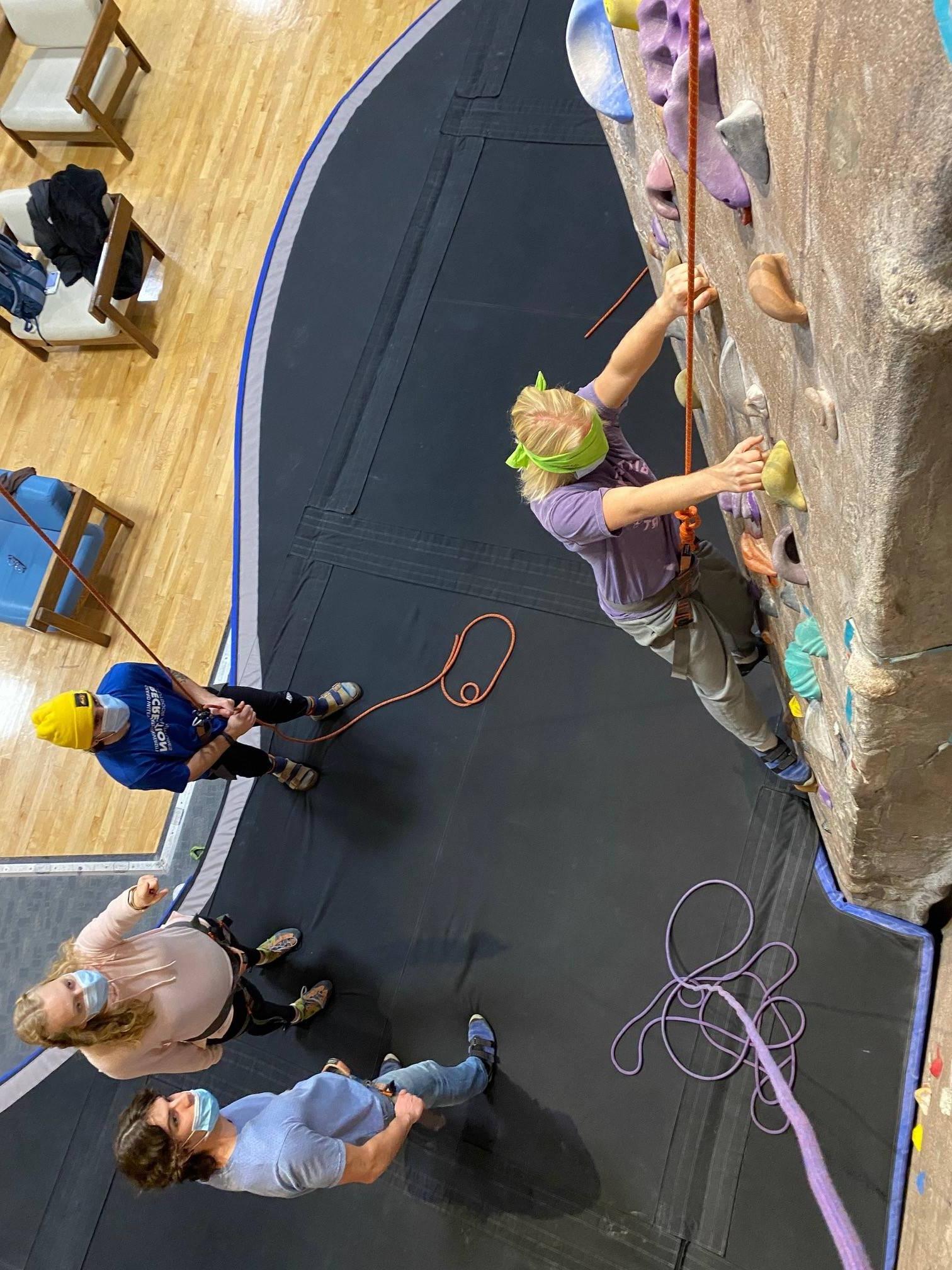 Climbing Center Staff belaying for blindfolded climber